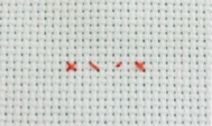 Piece of Aida material with a simple cross stitch indicated in red.  