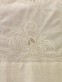 Detail of floral motif worked in Ayrshire whitewwork with central &lsquo;lace&rsquo; insets surrounded by satin stitch flowers, stems, leaves, and small eyelets (c. 1825, Scotland)