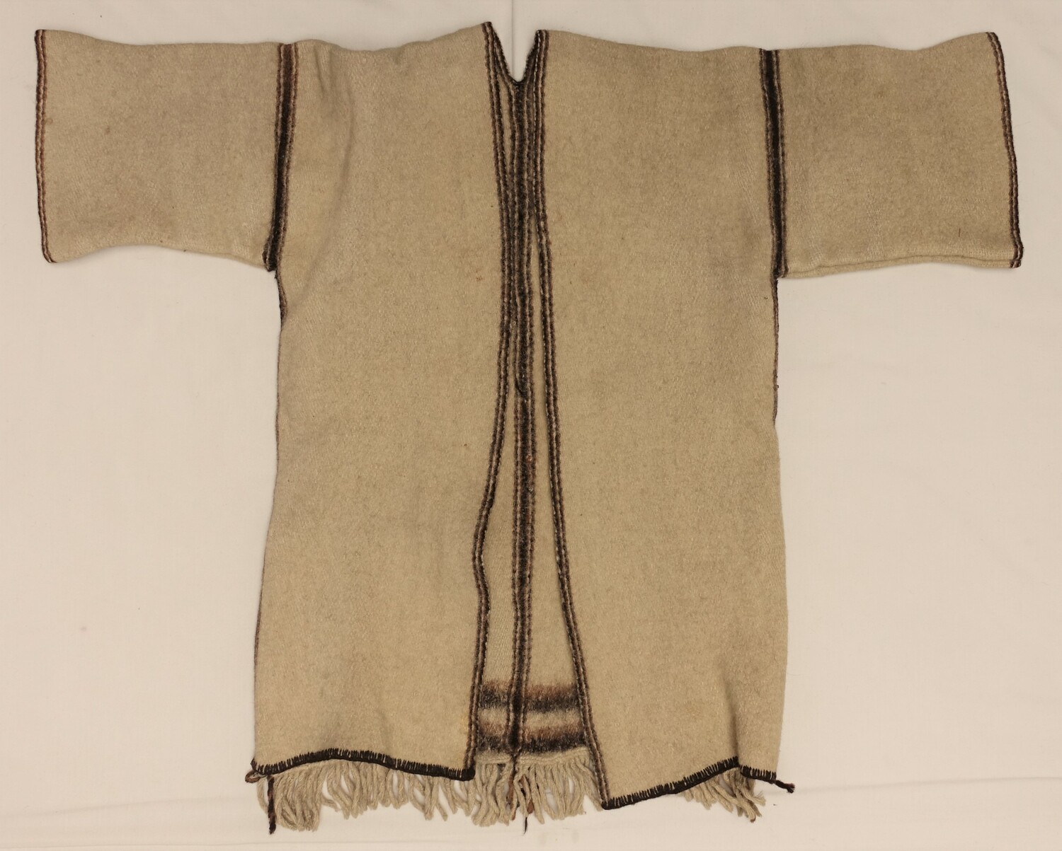 Jacket made from off-white, felted woollen cloth decorated around the neck and front opening, shoulder seam and sleeve hems with brown stripes. Nuristan, Afghanistan, 1960s (TRC 2022.1942).