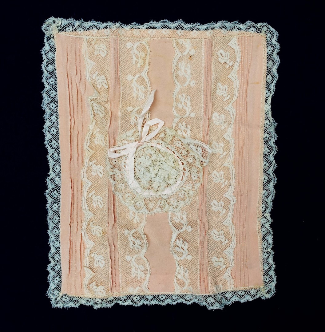 Pink bag decorated with pin tucks, as well as rows of bobbin lace and a rosette made out of lace. Late 19th - early 20th century. From the collection of  J. E. van Nierop, now housed at the TRC (TRC 2022.3151).