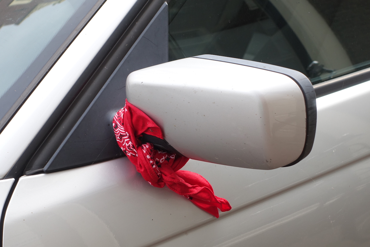Farmer's kerchief attached to a car's side mirror, in Leiden, 2 August 2022 (photograph author).
