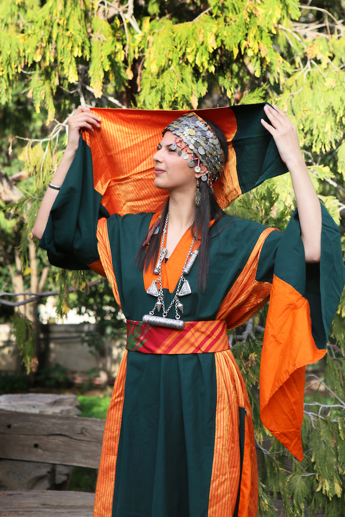 Model wearing a festive Ma'an dress from WIdad Kawar collection, with striped atlas material. She is also wearing the characteristic Ma'an headdress (arge). Photograph by Fatima Abbadi - Mignon Group.