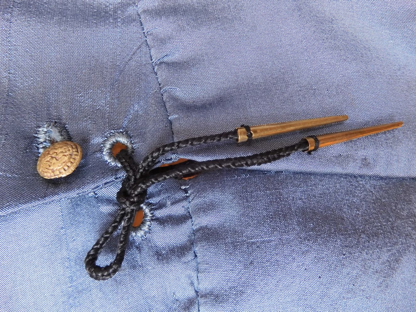 An aglet at the bottom of the buttons downs the centre front of a doublet c.1565-1570; the aglet is silk, woven on 2 tablets. Reconstruction and photo G.M. Kruseman.