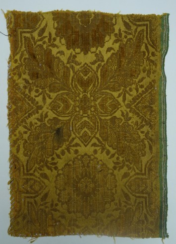 Early 17th century voided velvet sample, with cut and uncut pile (ciselé), satin ground and a green and white selvedge (TRC 2011.0376).