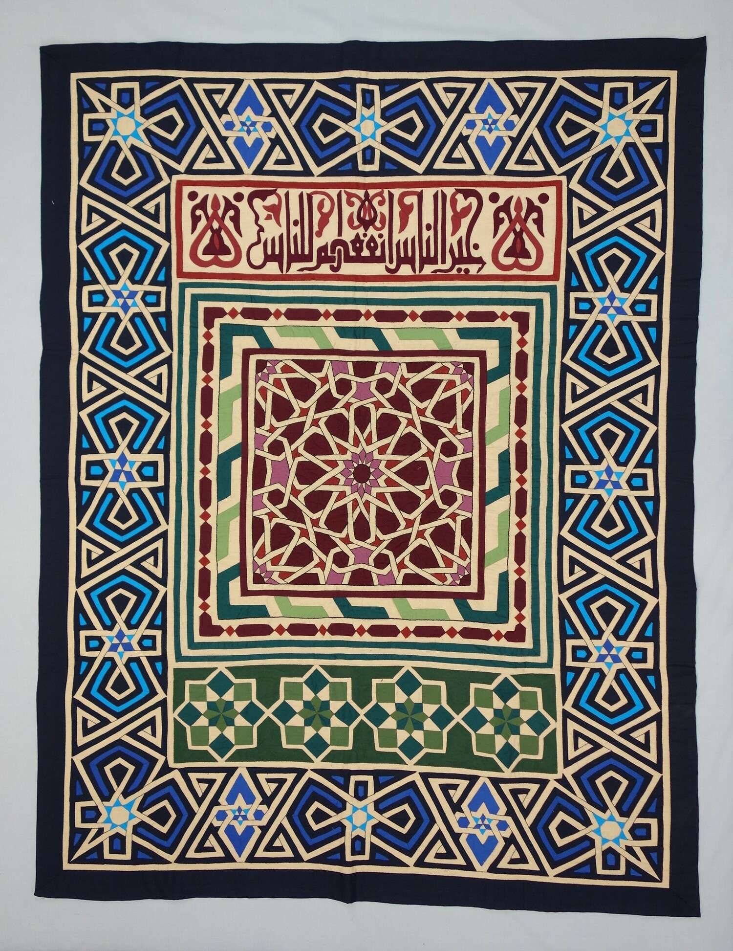 Khayamiya with part of a hadith in flourish Kufic, with a repeating and mirrored tile design in dark blue, mid-blue and turquoise on a pale fawn ground, Egypt, 2014 (TRC 2014.1066).