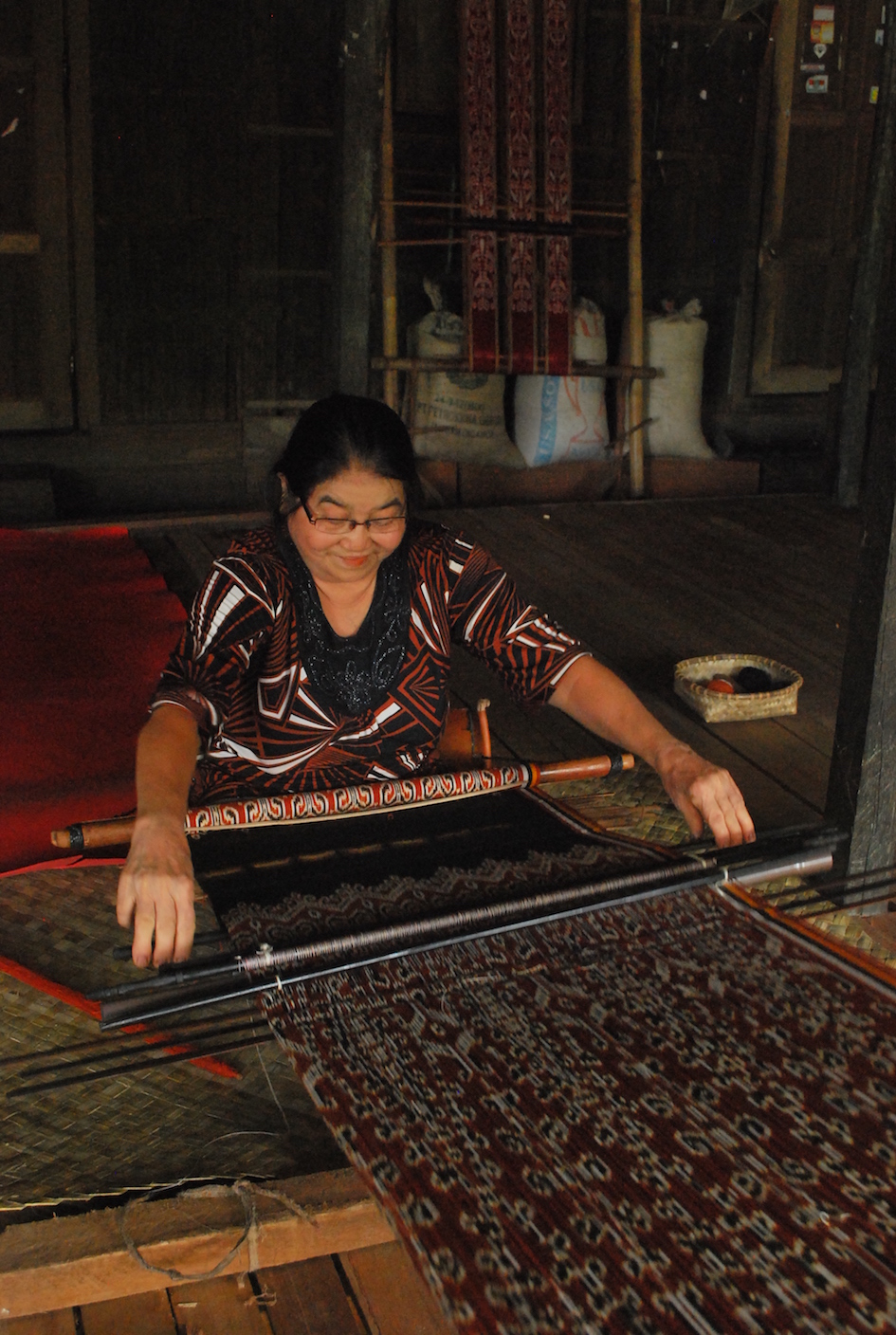 Ambachtsvrouw uit Sintang, Kalimantan, Indonesië, achter haar weefgetouw voor het maken van ikat. 